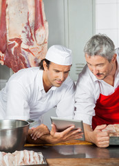 Butchers Using Tablet Computer At Counter
