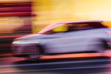 Obraz na płótnie Canvas White SUV Car in a Blurred City Scene
