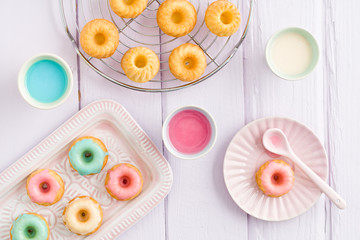 An overhead view of colorful mini doughnuts with pastel icing, elegantly arranged on decorative...