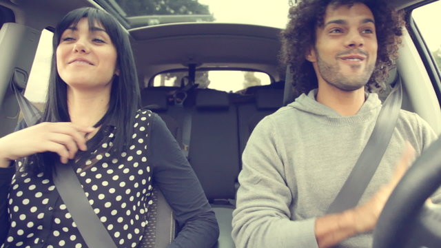 Handsome man driving car making girl dance funny