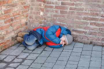 homeless boy leaned against the wall