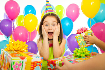 Joyful little kid girl receiving gifts at birthday party