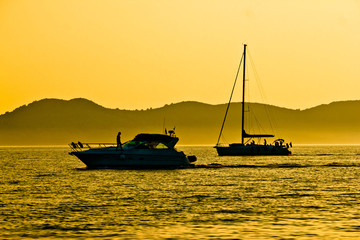 Yacht and sailboat silhouette at golden sunset