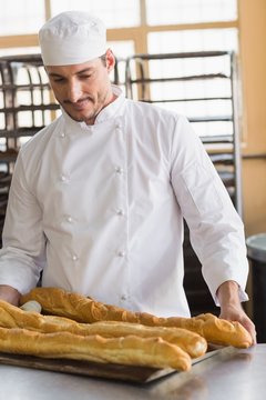 Baker looking at freshly baked baguettes