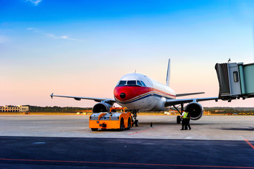 Airplane near the terminal in an airport at the sunset