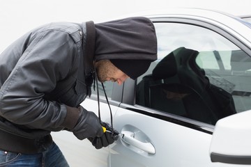 Thief breaking into car with screwdriver