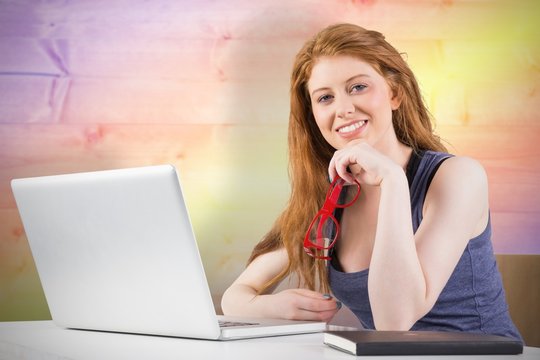 Composite image of pretty redhead working on laptop