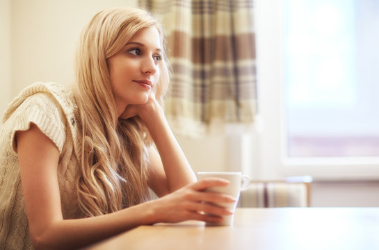 Young blonde woman with coffee cup at the table