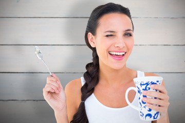 Composite image of pretty brunette having cup of tea