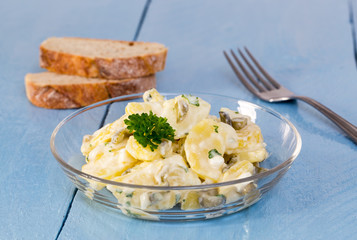 Kartoffelsalat in einer Glasschale auf Holz