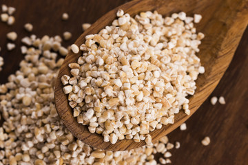 Barley groats on wooden spoon