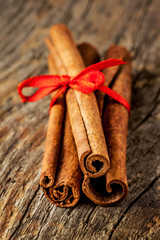 Cinnamon sticks with red bow close up (macro) on wood