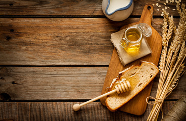Honing in een pot, boterham, tarwe en melk op vintage hout