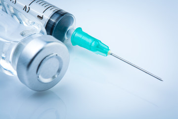 medical ampoules and syringe on blue background