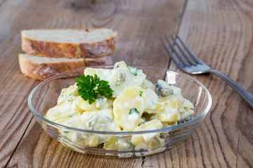 Kartoffelsalat in einer Glasschale auf Holz