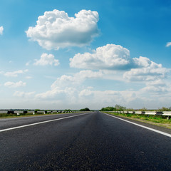 asphalt road closeup and low clouds in blue sky