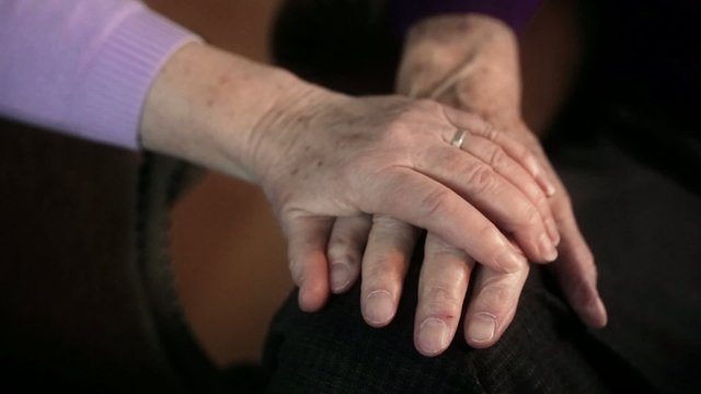 Woman caressing old mans hand