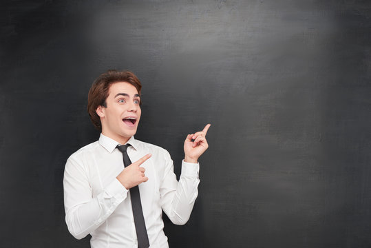 Funny man pointing at blank chalkboard
