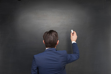 Businessman writing something on chalkboard