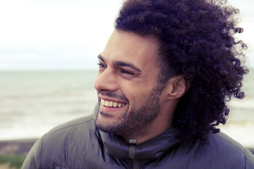 Handsome happy man smiling in winter in front of the ocean retro
