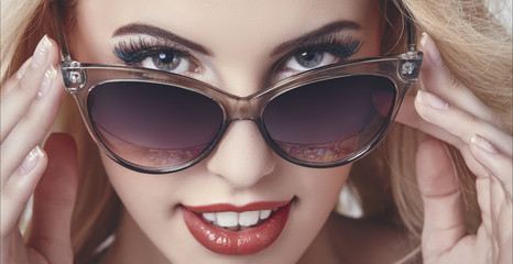 Seductive happy woman looking over sunglasses