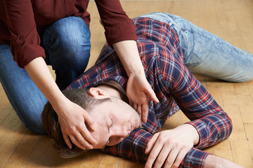 Woman Placing Man In Recovery Position After Accident - obrazy, fototapety, plakaty