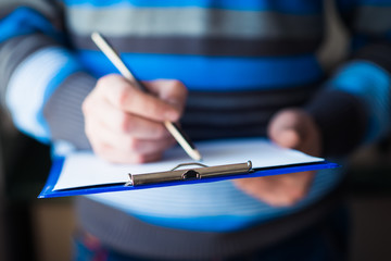 businessman holding a clipboard and write on it