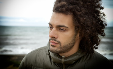 Sad lonely man thinking in front of the ocean in winter