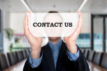 Businessman Holding Sign Contact Us. Office background