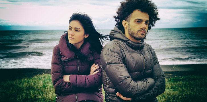 Unhappy man and woman outdoors after fight in front of the ocean