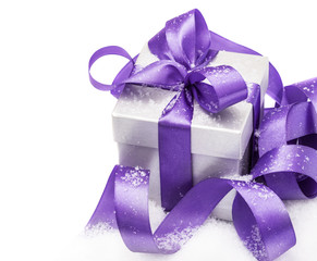 Gift box with a lilac bow on snow isolated on the white