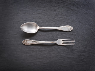 Silver cutlery on a dark grey background.