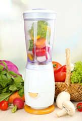Blender with fresh vegetables on kitchen table