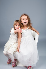 Two little funny and laughing girl in white clothes