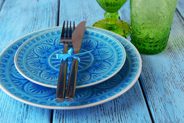 Empty colorful plate, glasses and silverware set on wooden