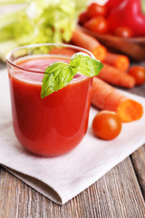 Glass of tomato juice with vegetables on wooden table close up