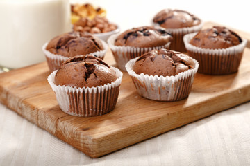 Delicious chocolate muffins on wooden board 