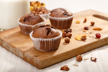 Delicious chocolate muffins on wooden board 