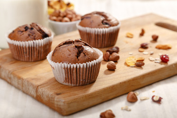 Delicious chocolate muffins on wooden board 