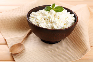 Cottage cheese in bowl with spoon on napkin on wooden