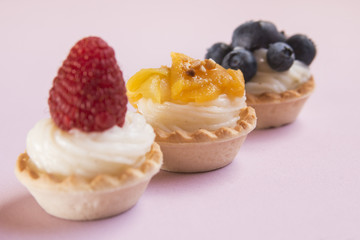 Sweet tartlets filled with cream and blueberry, raspberry and ma