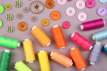 Colorful buttons and sewing threads on wooden background
