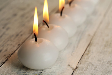 Burning candles on wooden table close-up