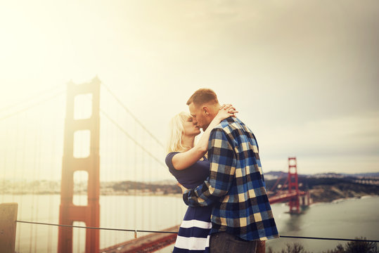 romantic couple kissing at golden gate bridge with lens flare