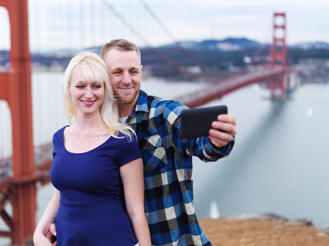 couple taking selfie in front of golden gate bridge