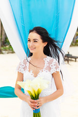 Wedding ceremony on a tropical beach in blue. Happy bride under