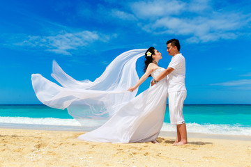 Fototapeta na wymiar Asian bride and groom on a tropical beach. Wedding and honeymoon