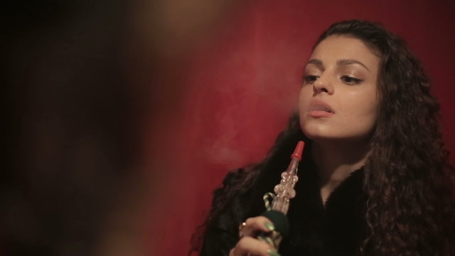 Arabian woman smoking shisha or hookah. Close up.