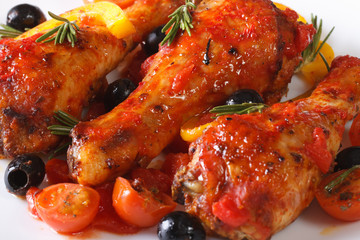 Delicious chicken legs in tomato on a plate, macro horizontal