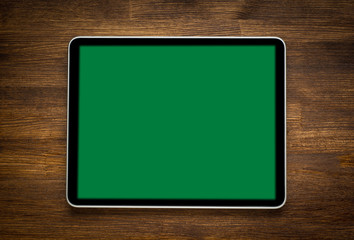 Blank modern digital tablet on a wooden desk. Top view.